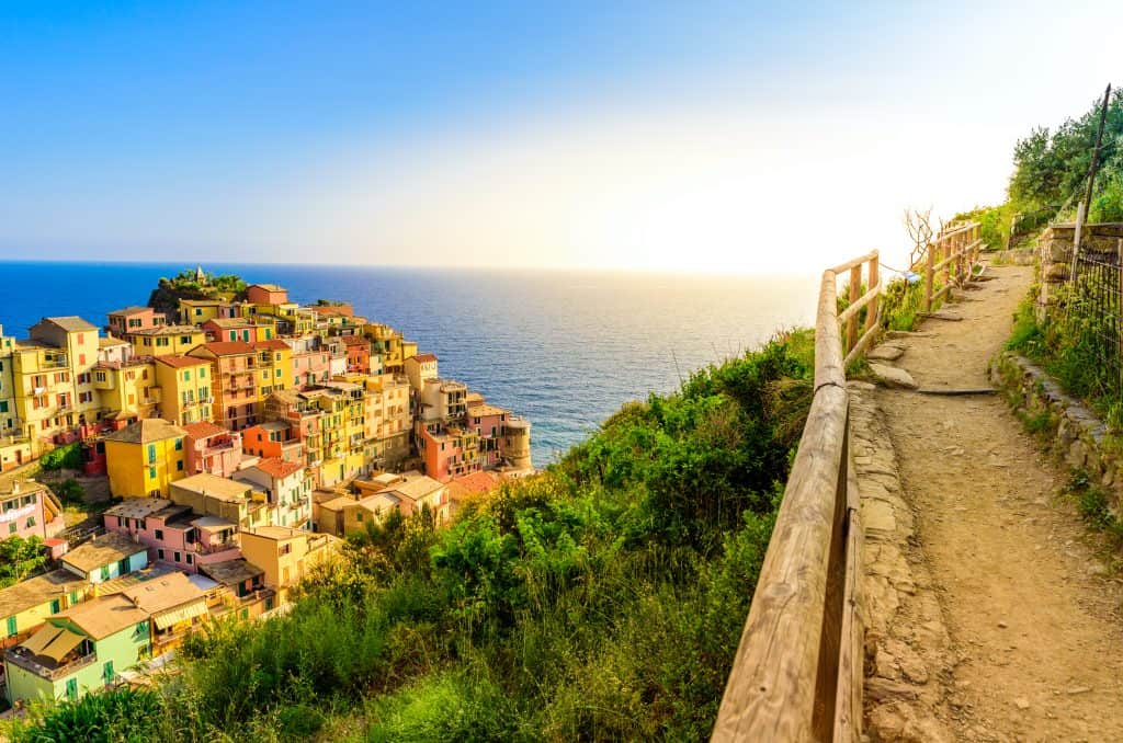 Cinque Terre coastal hiking trail with colorful cliffside villages and clear blue sea.